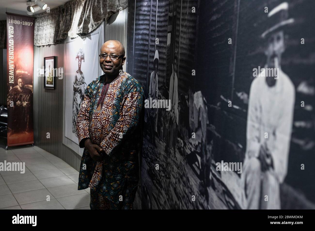 The director of the national museum in Benin city infront of a photograph depicting British in the royal palace surrounded by looted Benin Bronzes Stock Photo