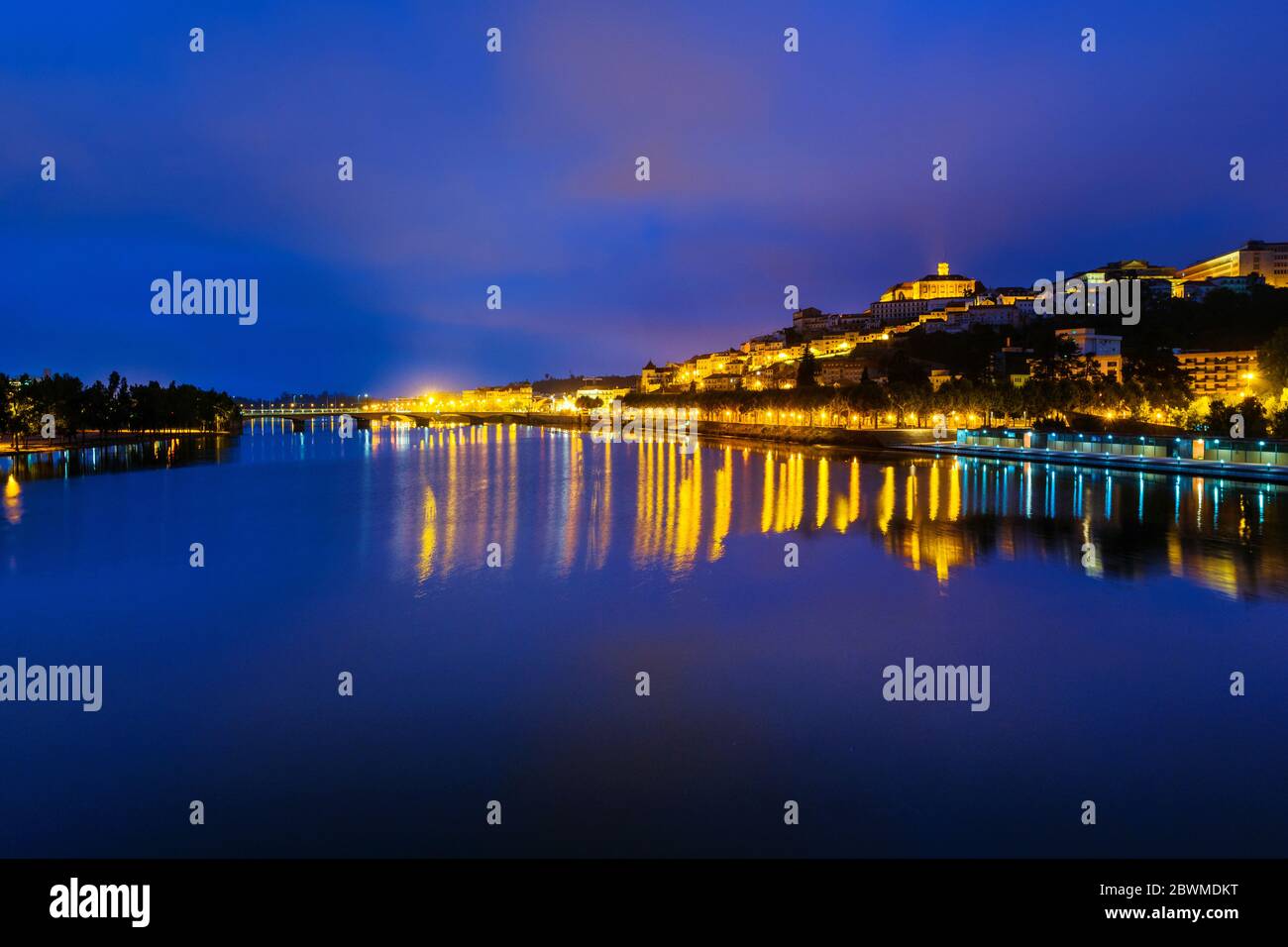 Coimbra, Portugal. Night view of Coimbra, Portugal historical site with illuminated landmarks and lights. Reflection in the river, colorful violet clo Stock Photo