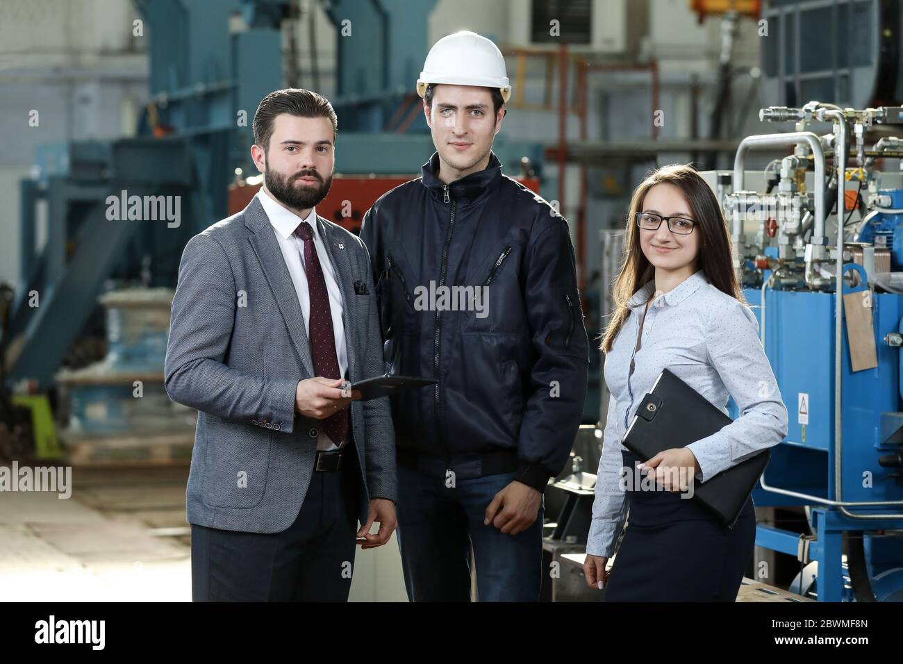 Portrait of a solid businessman with his secretary and factory engineer ...