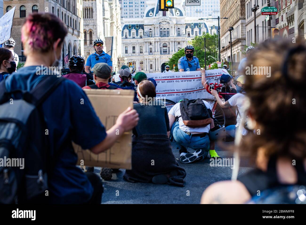 Philadelphia, Pennsylvania / USA. Protesters kneel in front of bike-mounted police. The reason was unclear, but after a line of police vehicles made a U-turn on Broad street back towards city hall the bike police dispersed. The crowd focused on the officer on the left for not wearing a face mask, calling him out for increasing health risks during the coronavirus pandemic. June 01, 2020. Credit: Christopher Evens/Alamy Live News Stock Photo