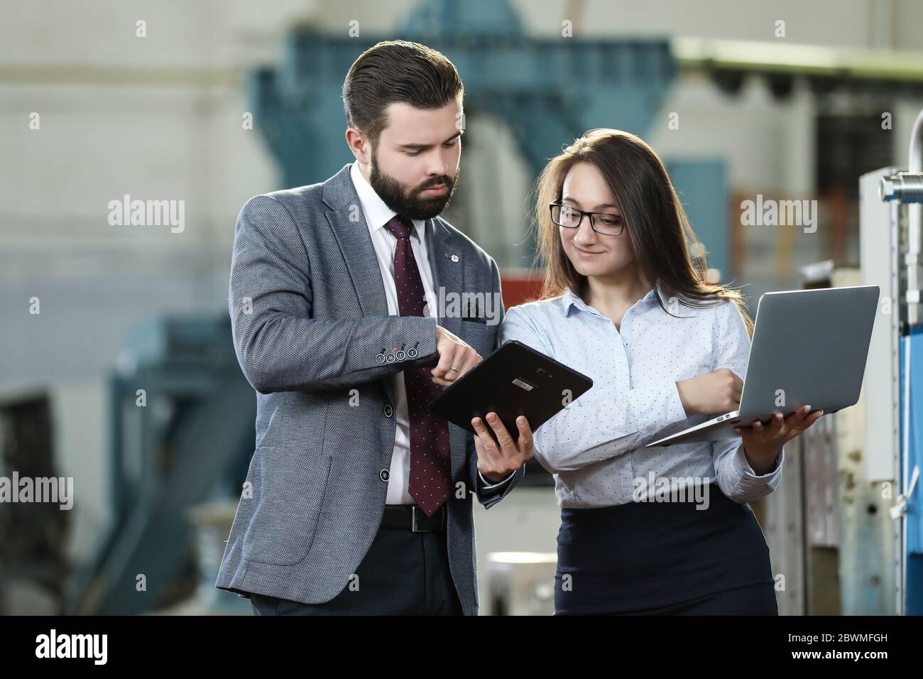 Portrait of a solid businessman with his secretary holding laptop and ...