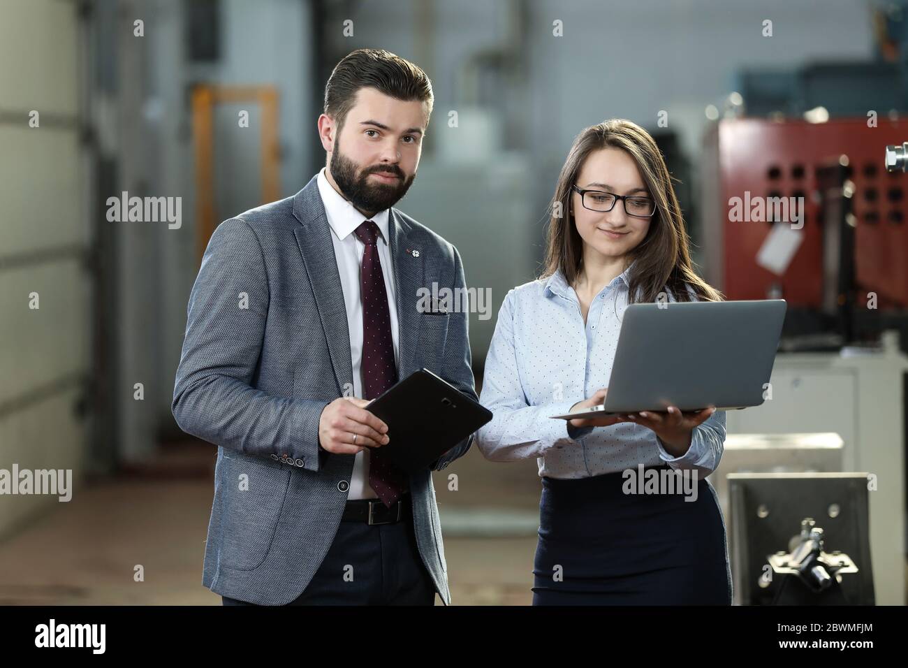 Portrait of a solid businessman with his secretary holding laptop and ...