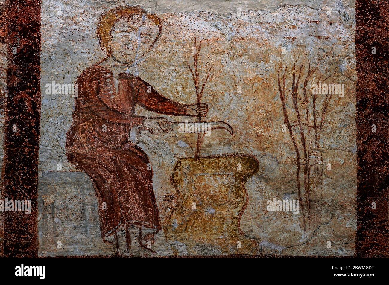 Pruning saplings by hand with a billhook or knife.  Detail of medieval Labours of the Months fresco cycle, painted in ochre in primitive or rustic style. In the cloister attached to the Chiesa di San Nicola (Church of St Nicholas) at the Abbazia di Piona (Piona Abbey), beside Lake Como at Colico, Lombardy, Italy. Stock Photo