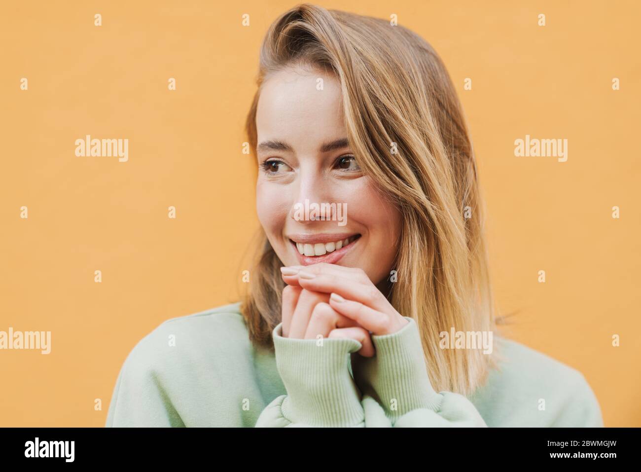 Portrait of happy blonde woman smiling and looking aside isolated over ...