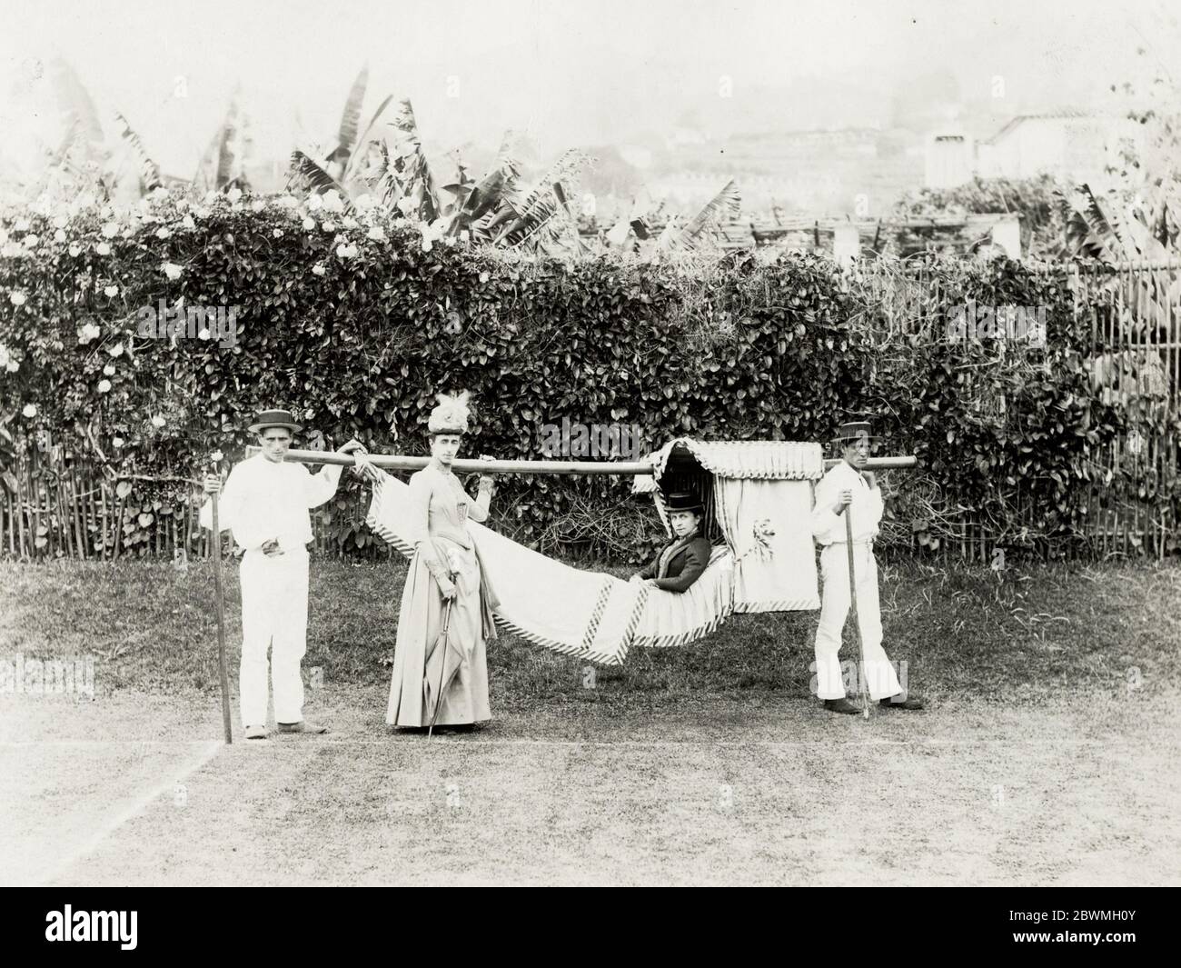 Vintage 19th century photograph - woman being carried in a hammock, carrying chair, probably Madeira or Canary Islands. Stock Photo