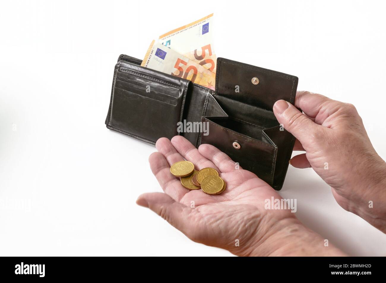 Hands of an elderly woman with a money purse and few euro coins and banknotes, cash check in the economic crisis affected by coronavirus, white backgr Stock Photo
