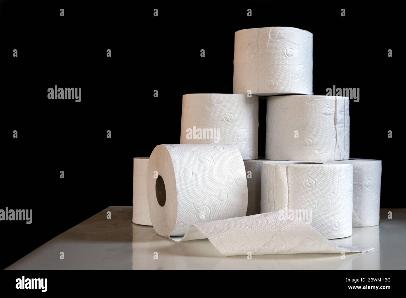 Several rolls of toilet paper, shortage in Germany after shoppers panic buying because of coronavirus pandemic outbreak, dark background with copy spa Stock Photo