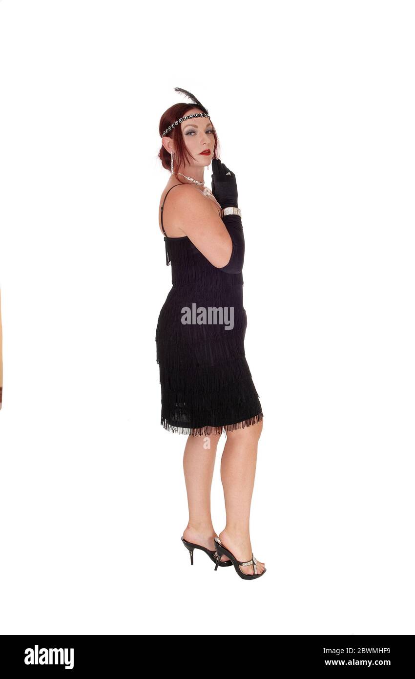 A beautiful woman standing in a black dress in profile with her  red hair and head band and cloves, isolated for white background Stock Photo