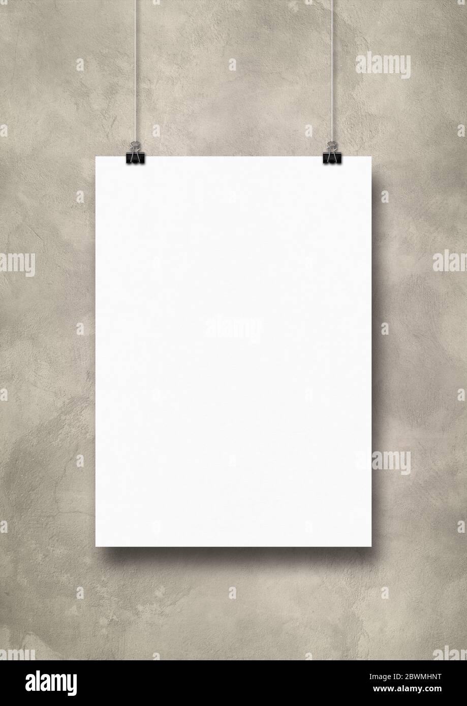 White poster hanging on a light concrete wall with clips. Blank mockup