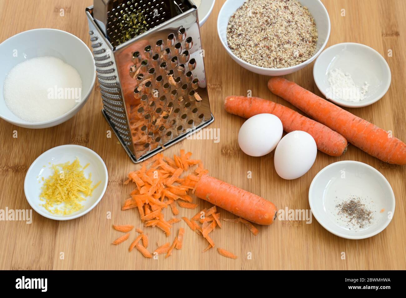 Grated carrots, ground almonds, eggs and spices, baking ingredients on a wooden kitchen board for an Easter carrot cake, selected focus, narrow depth Stock Photo