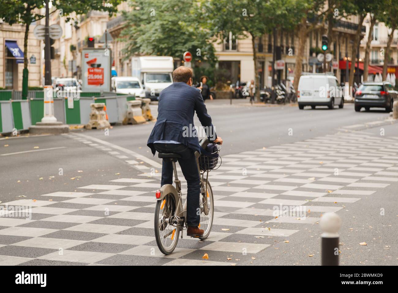 Paris, France - July 13 2019: Businessman riding bicycle to work on Parisian street Stock Photo