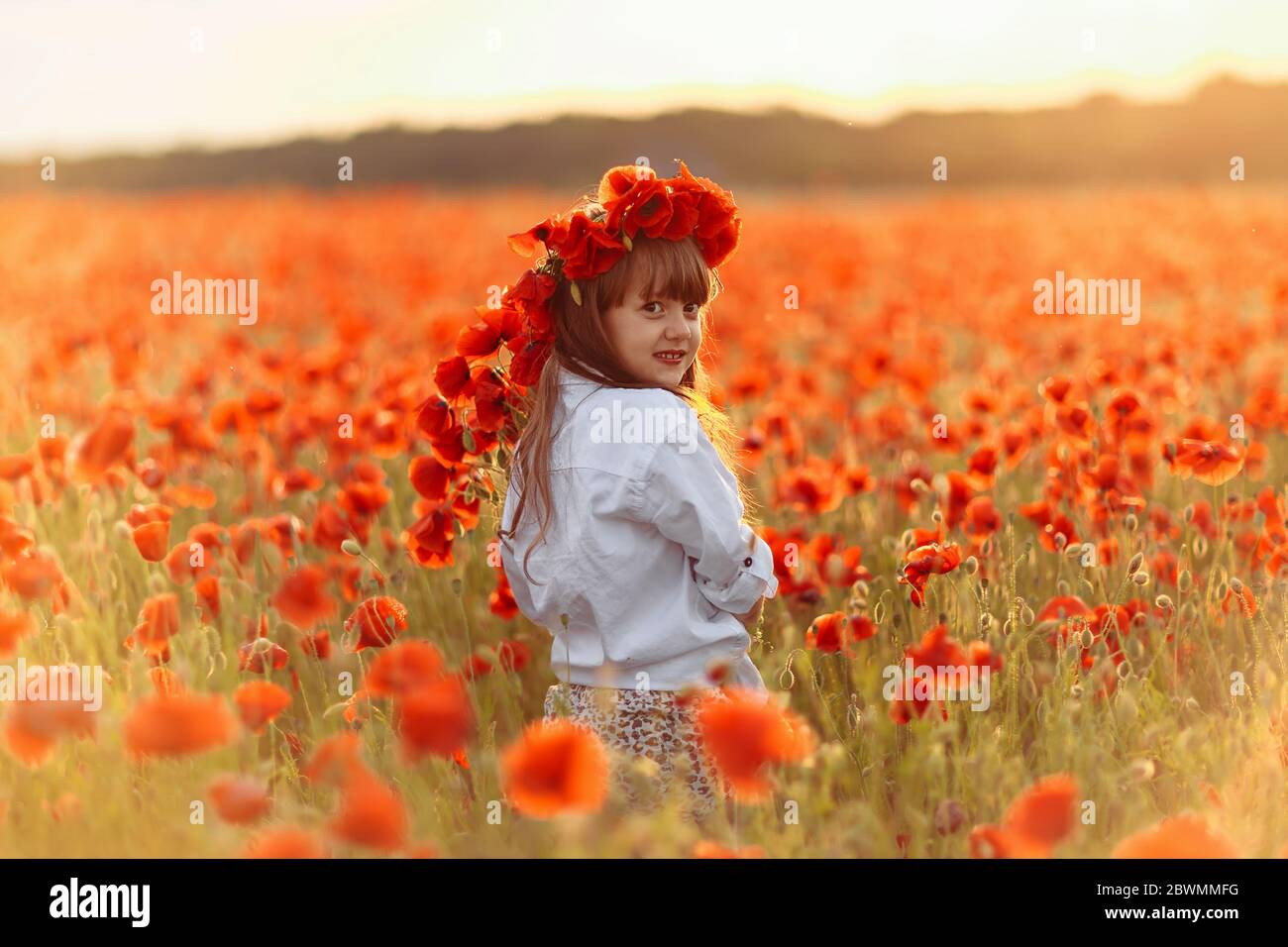Little cute girl in white dress posing in wreath on her head with a ...