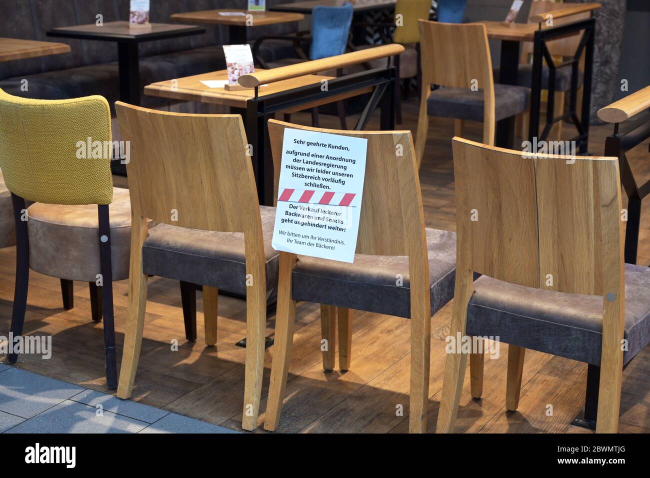 Ratzeburg, Germany, March 20, 2020: Chairs stand as a barrier in front of a café and a german massage shows that it was closed due to the spread of co Stock Photo