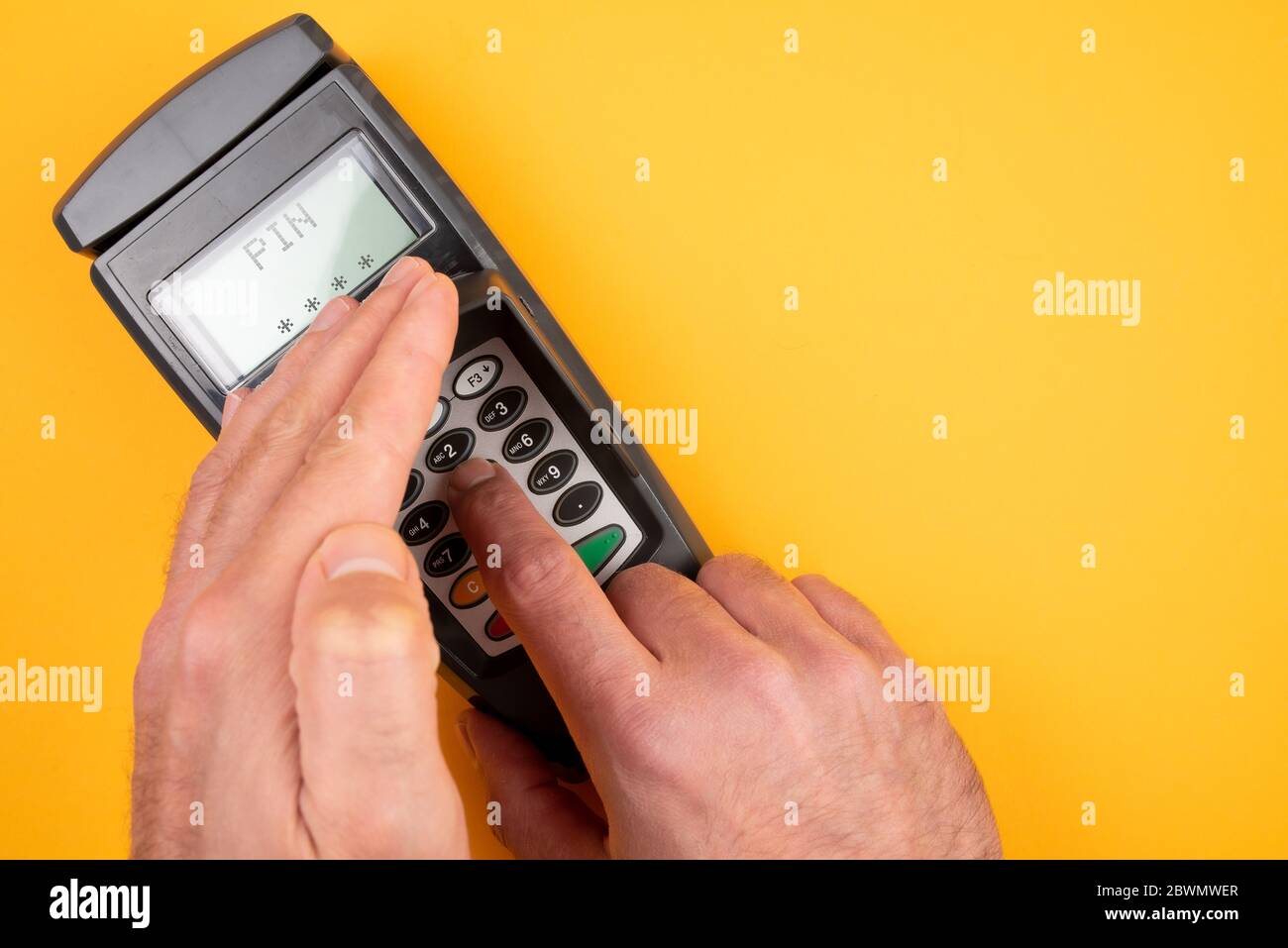 person typing in PIN at POS payment terminal while covering keypad with free hand to prevent spying out of personal data Stock Photo