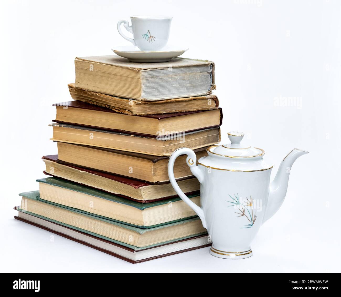 a stack of old books and an elegant coffee set. On white background. Stock Photo