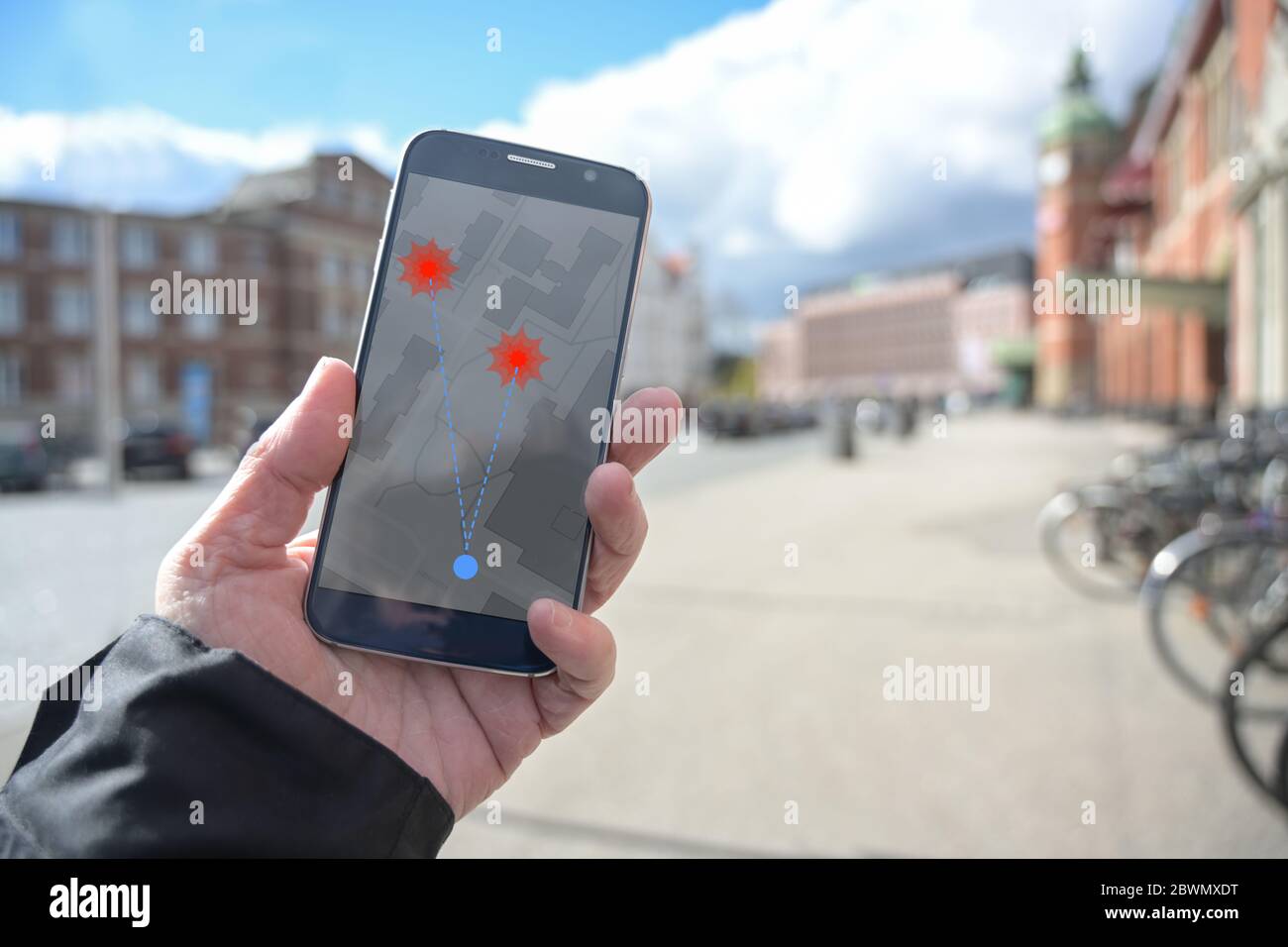 Hand with mobile phone and coronavirus tracking  app via bluetooth against the spread of the pandemic, but controversial when it comes to protection o Stock Photo