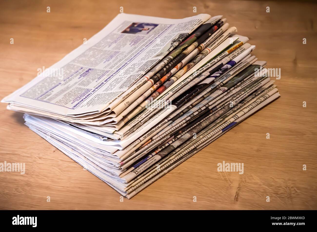 Newspapers folded and stacked on the table with wood background. Closeup newspaper and selective focus image. Time to read concept. Stock Photo