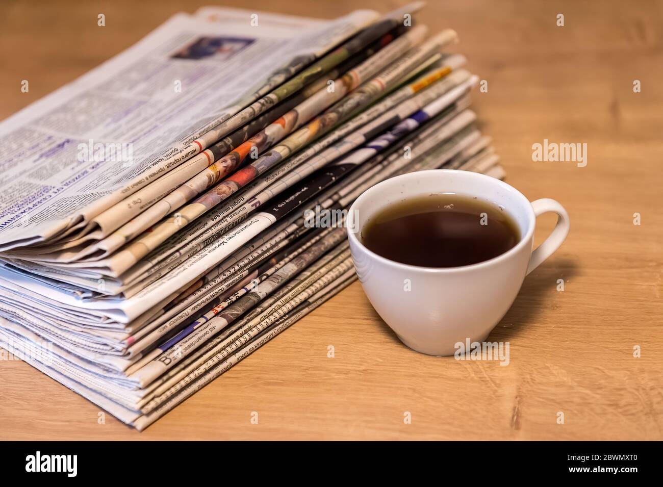 selective focus of the cup of tea stacking newspapers folded place on wooden table Stock Photo