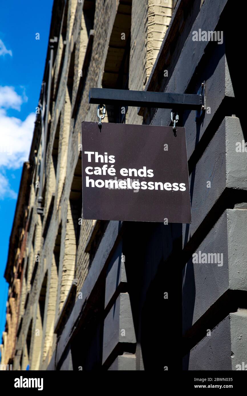 'This Cafe ends homelessness' sign on facade to Crisis homeless charity cafe in partnership with Volcano Coffee Works, Spitalfields, London, UK Stock Photo