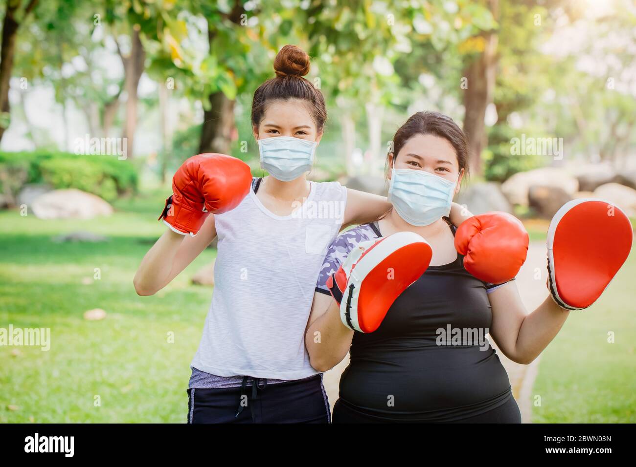 People doing sport boxing activity with friend and wear face mask for stimulate immunity at outdoor park. Stock Photo
