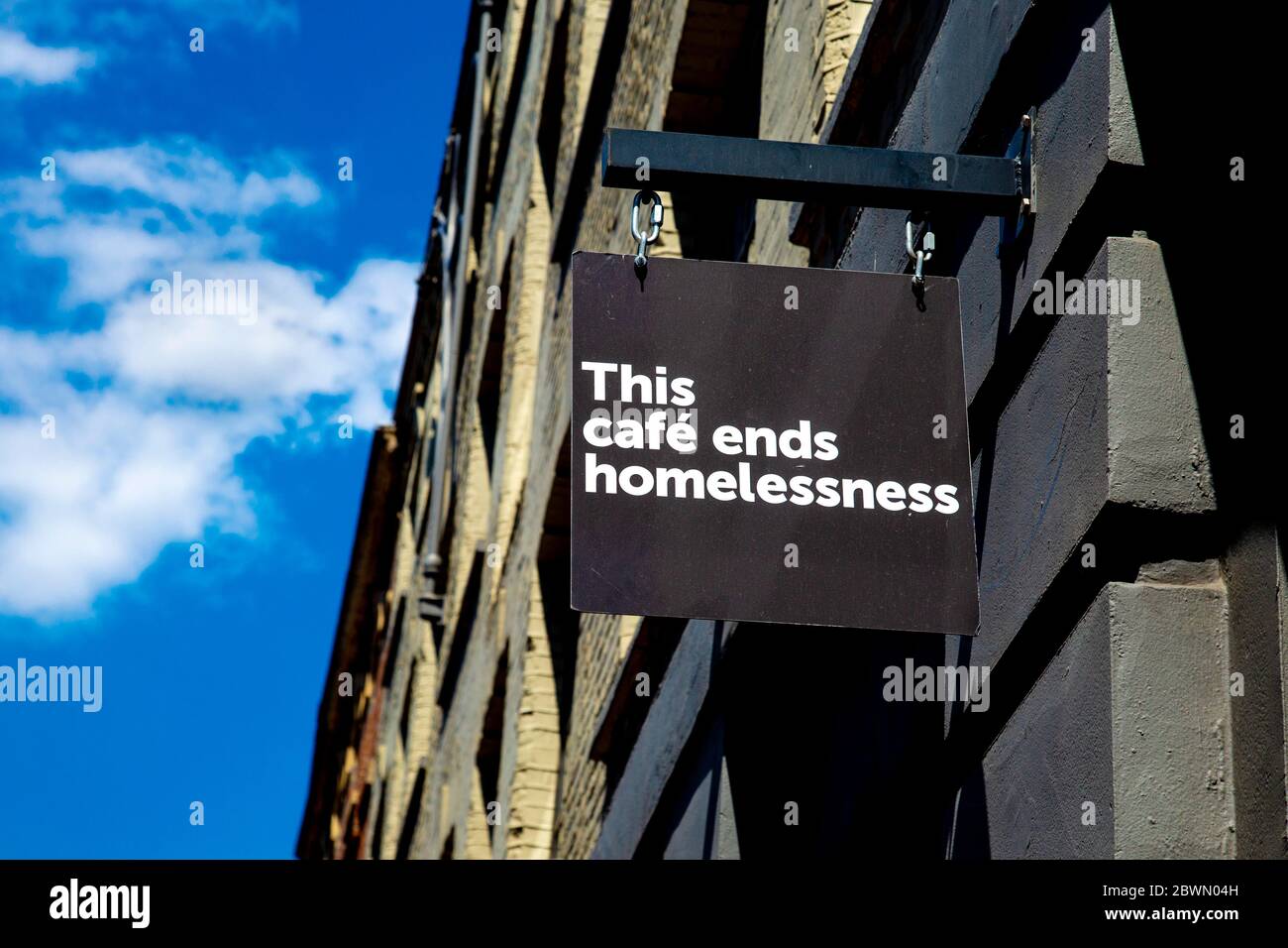 'This Cafe ends homelessness' sign on facade to Crisis homeless charity cafe in partnership with Volcano Coffee Works, Spitalfields, London, UK Stock Photo
