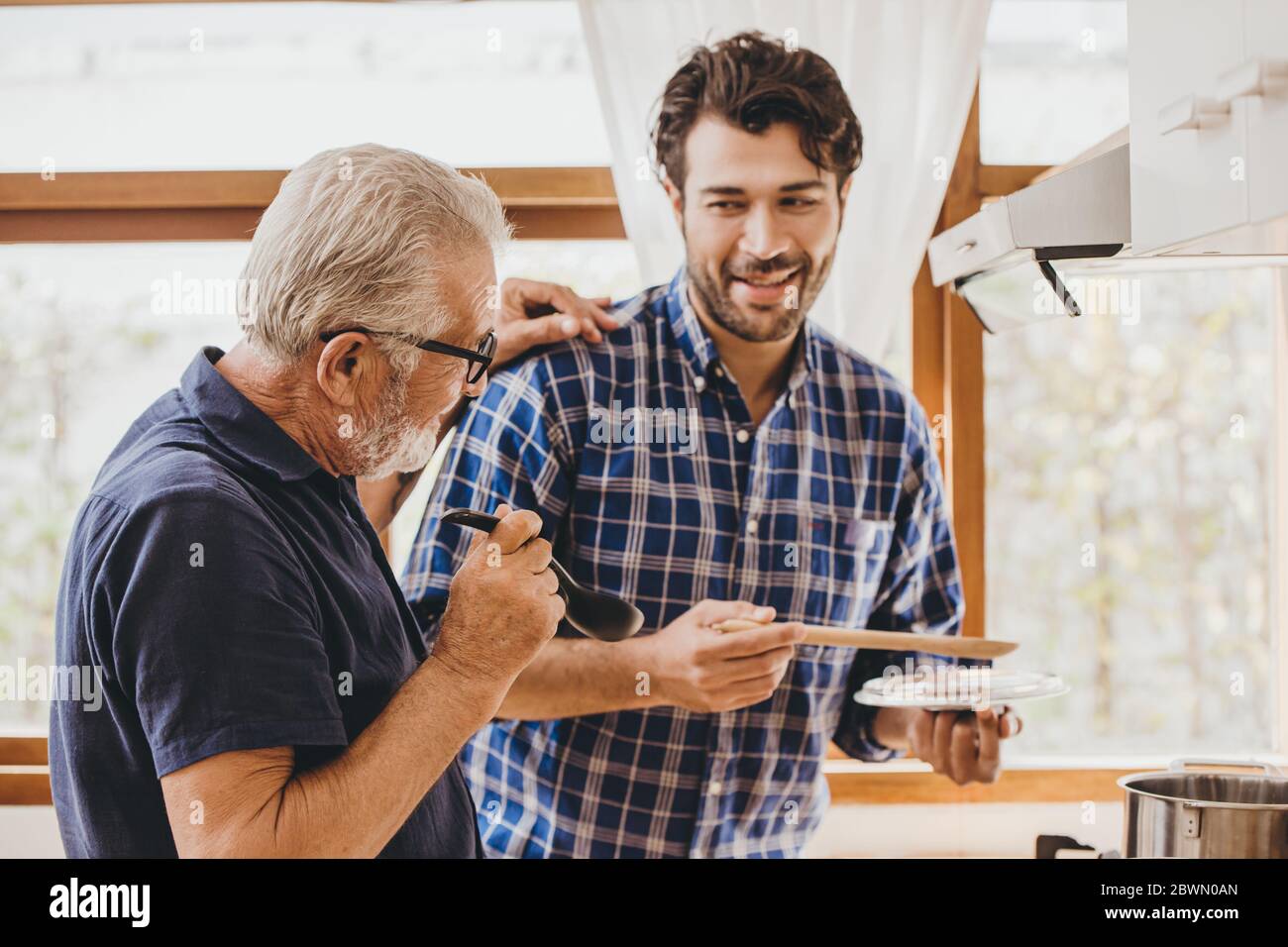 Happy senior elderly man enjoy cooking with family at the kitchen for stay home leisure activity and lifestyle of people. Stock Photo