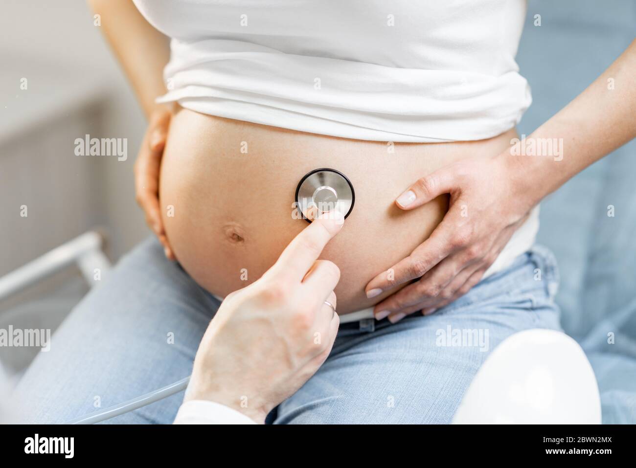 Doctor listening to a pregnant woman's belly with a stethoscope during a  medical examination, close-up view Stock Photo - Alamy