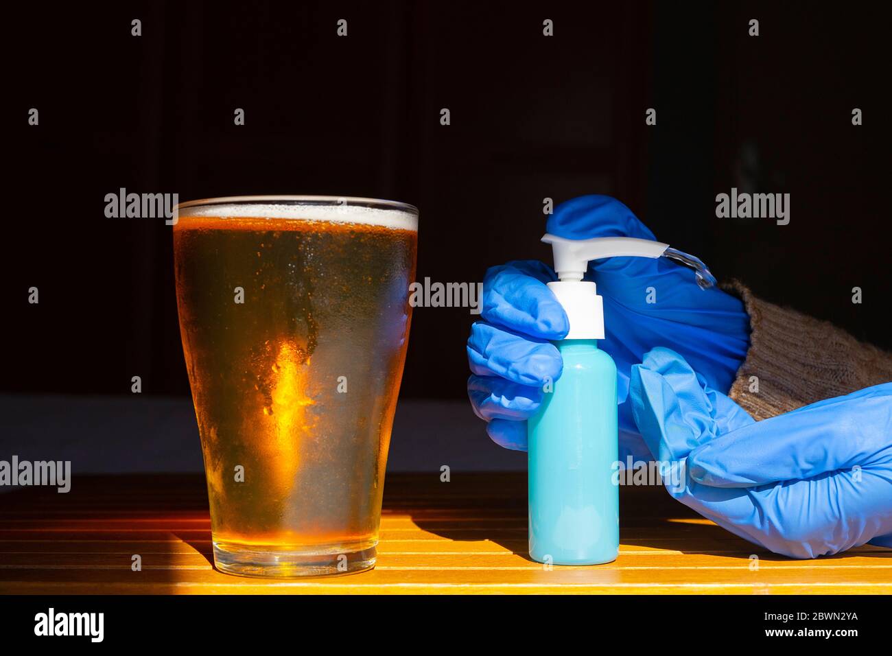 Person with gloves and disinfectant having a beer in a restaurant