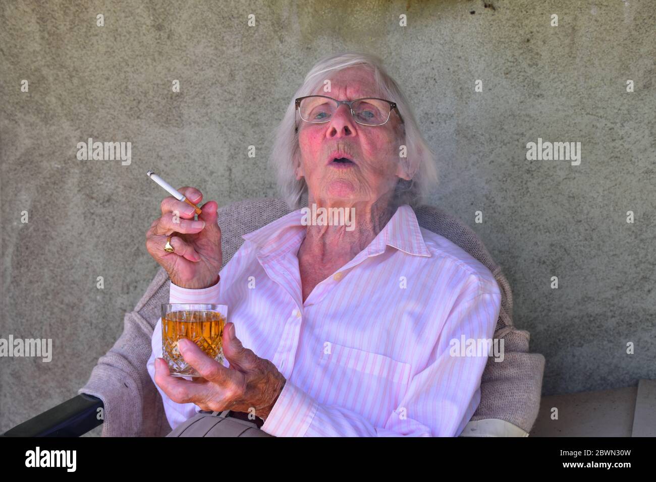 Old lady smoking a cigarette and drinking a brandy Stock Photo Alamy