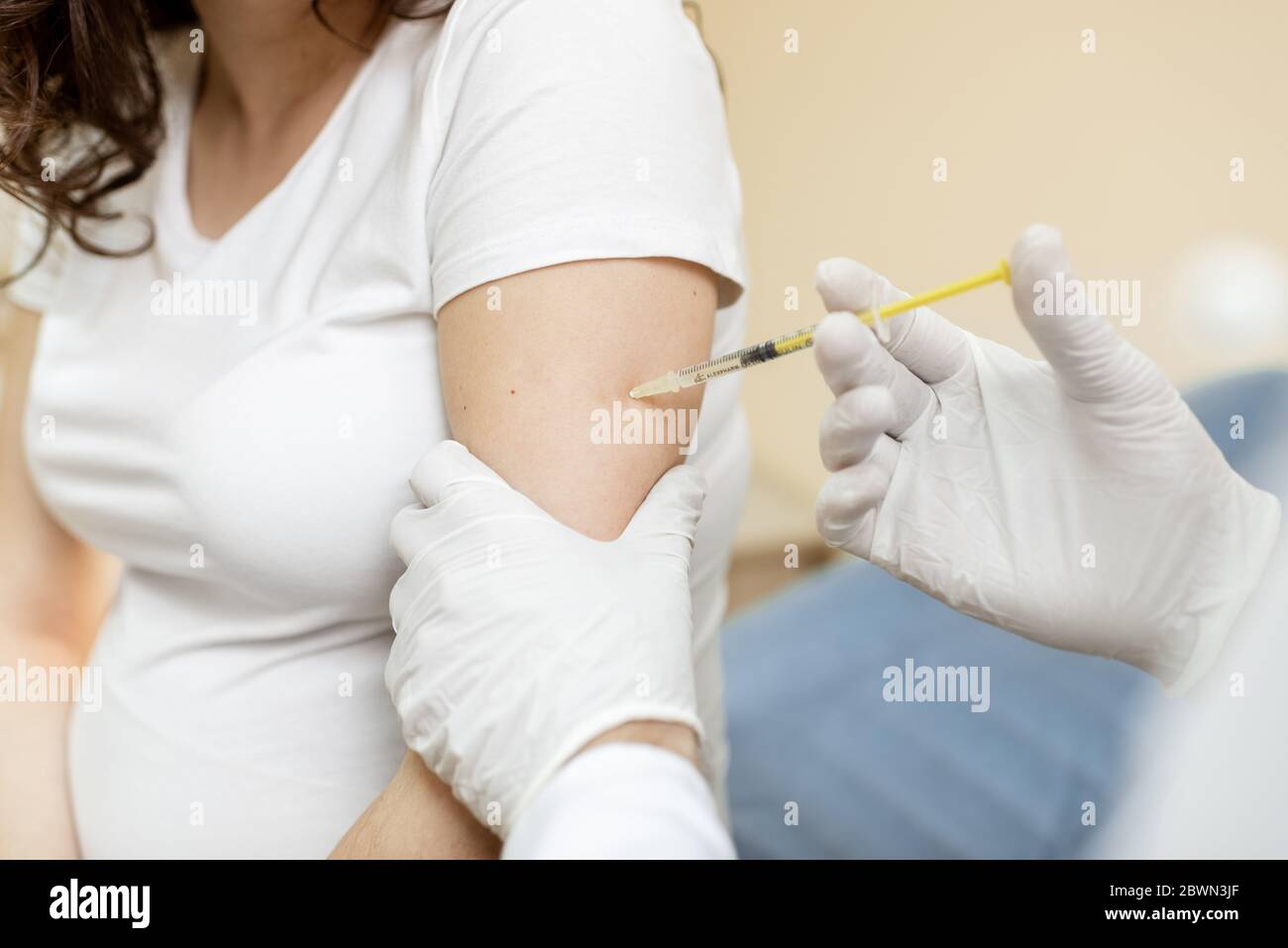Vaccine injection procedure for a pregnant woman, cropped view without face Stock Photo
