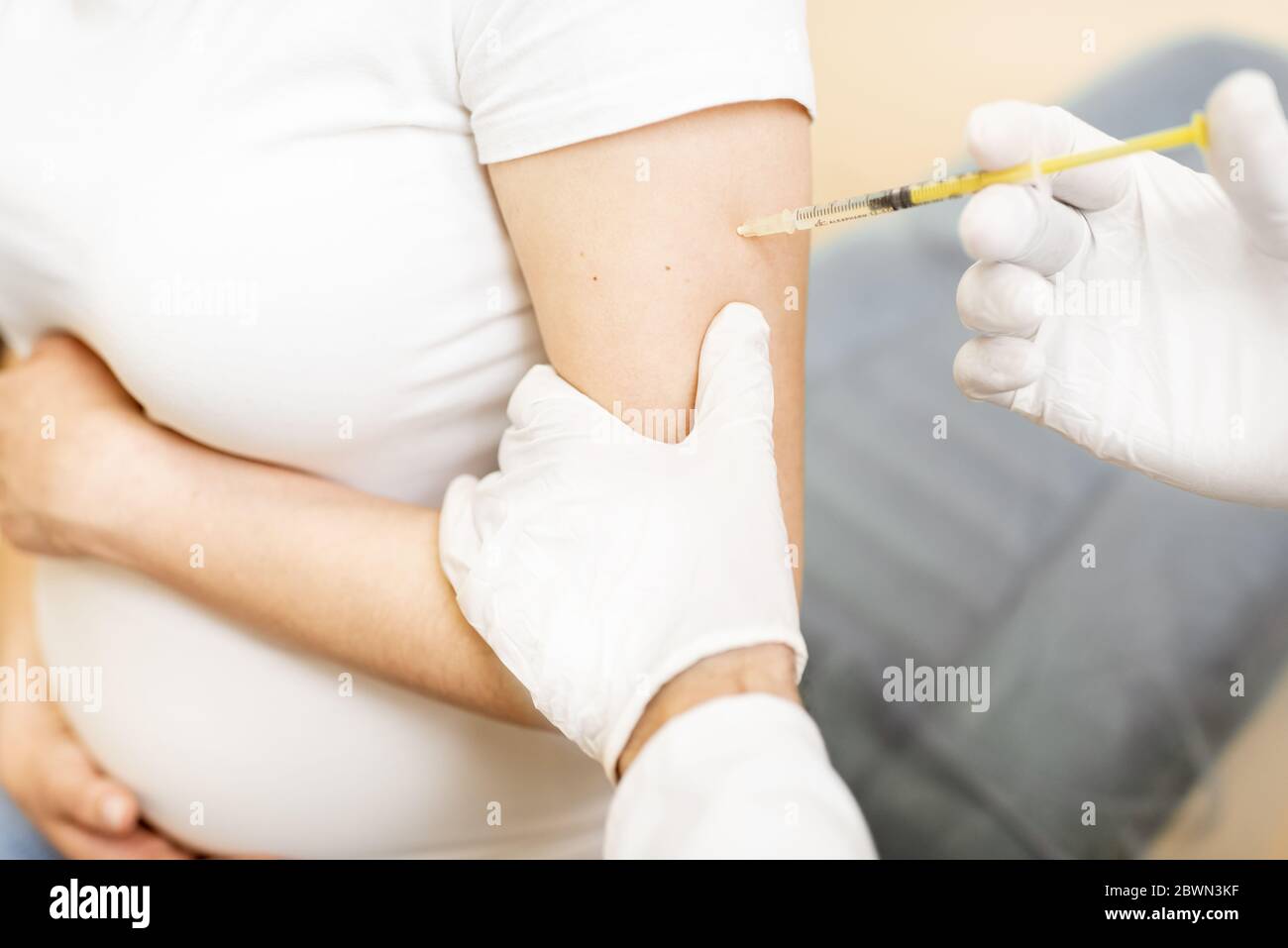 Vaccine injection procedure for a pregnant woman, cropped view without face Stock Photo