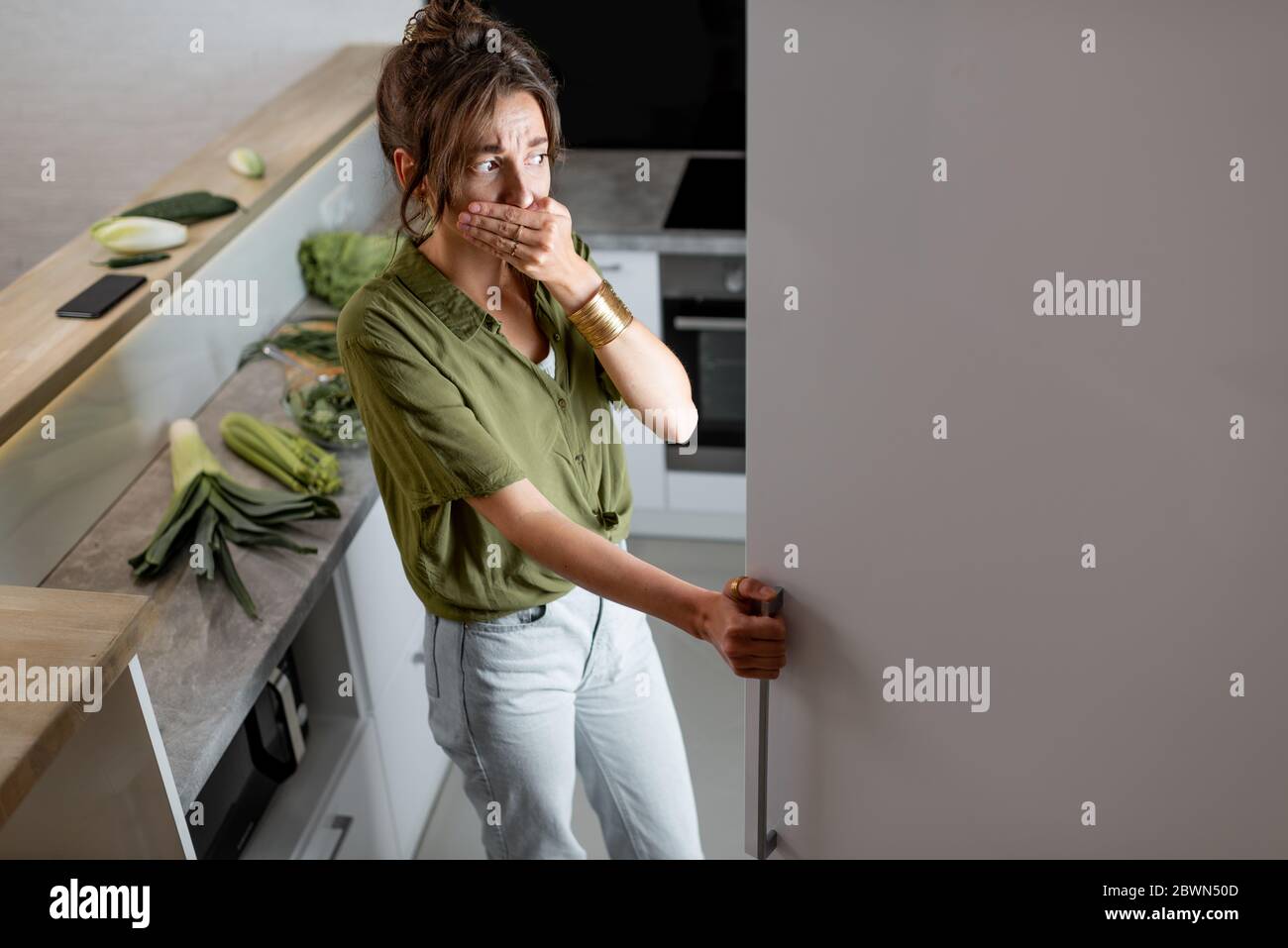 Young woman looking into the fridge, feeling hungry at night. Concept of not regular eating and overeating at night Stock Photo