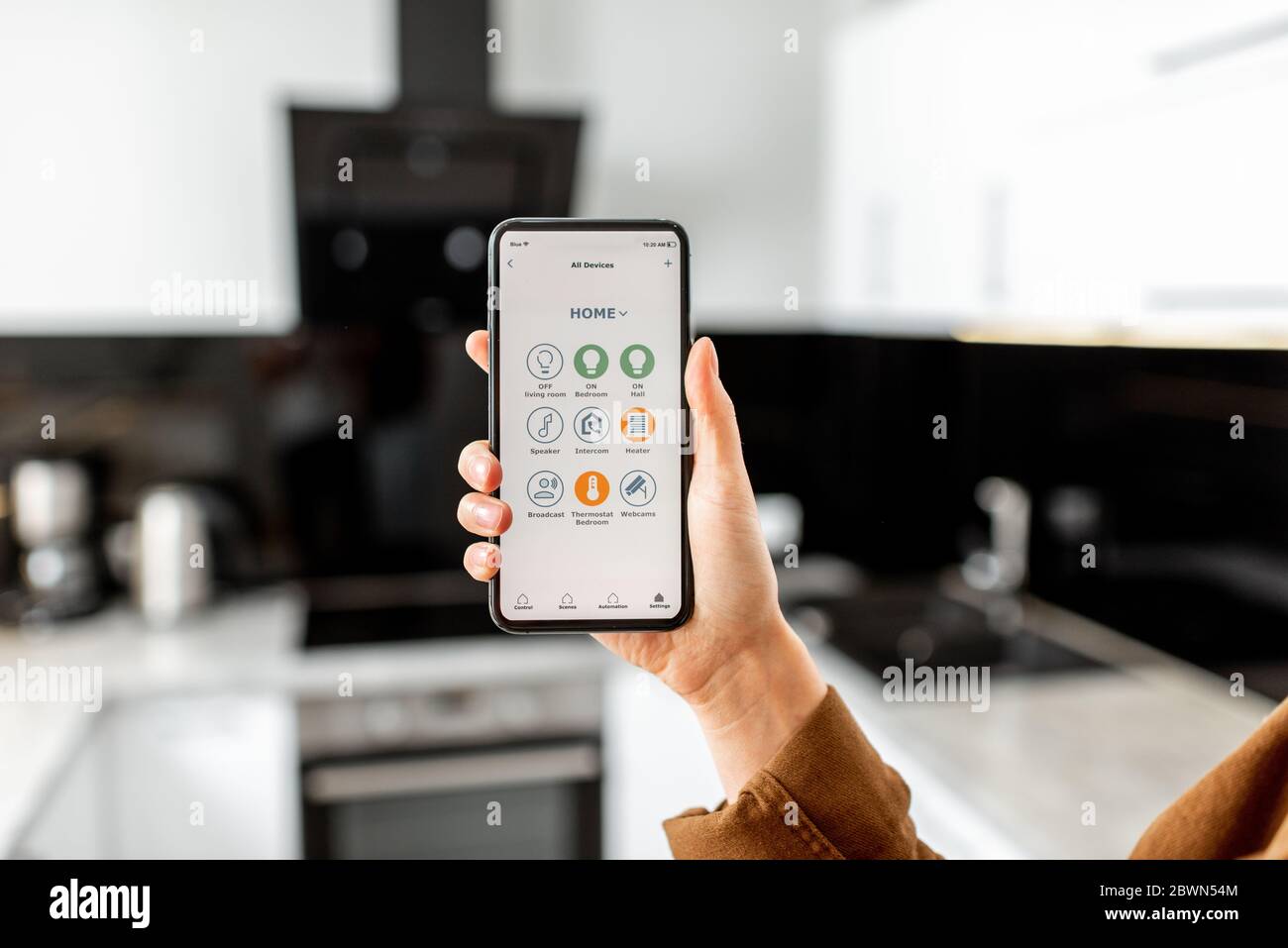 Woman controlling kitchen appliances with a smart phone, close-up on mobile device with launched smart home application. Smart home concept Stock Photo