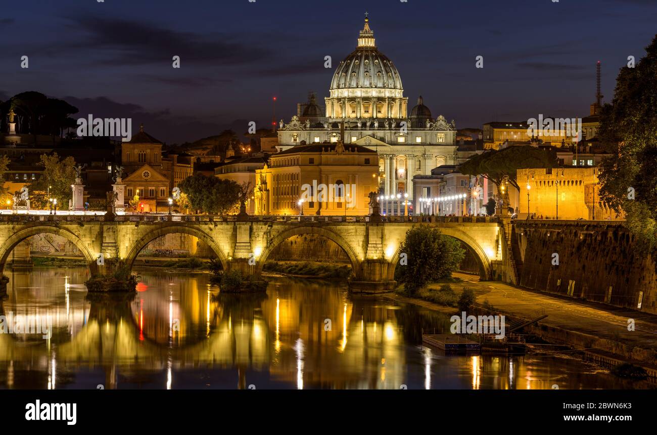 Rome at Night - A panoramic night view of Tiber river at Sant' Angelo Bridge, with St. Peter's Basilica towering in background, Rome, Italy. Stock Photo