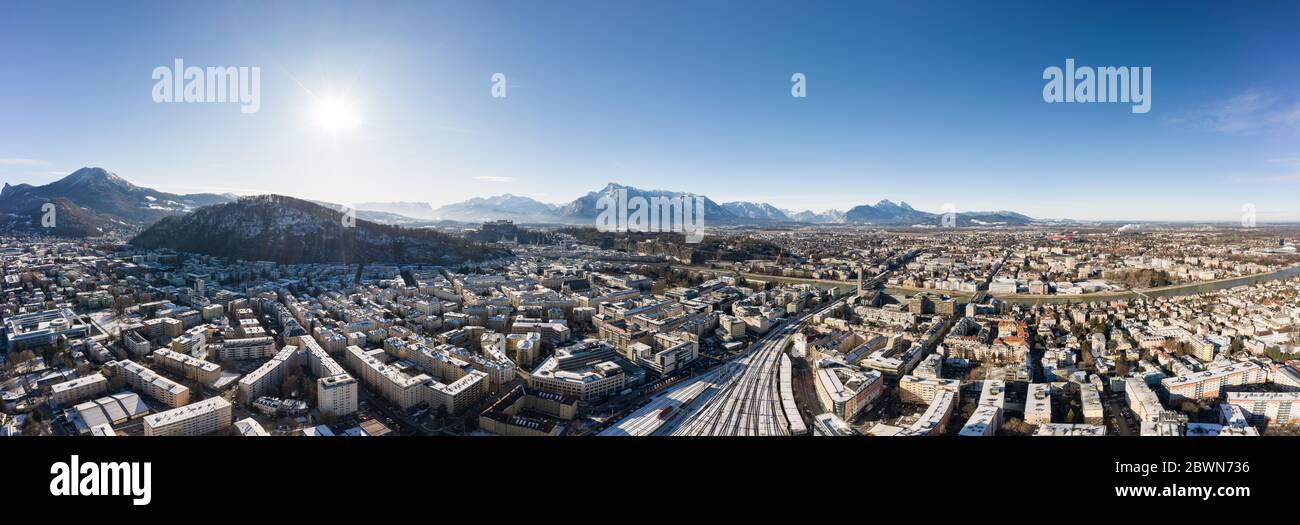 Panoramic aerial drone view of Salzburg snowy old town with view of Unesberg Kapuzinerberg mountain and train station Stock Photo