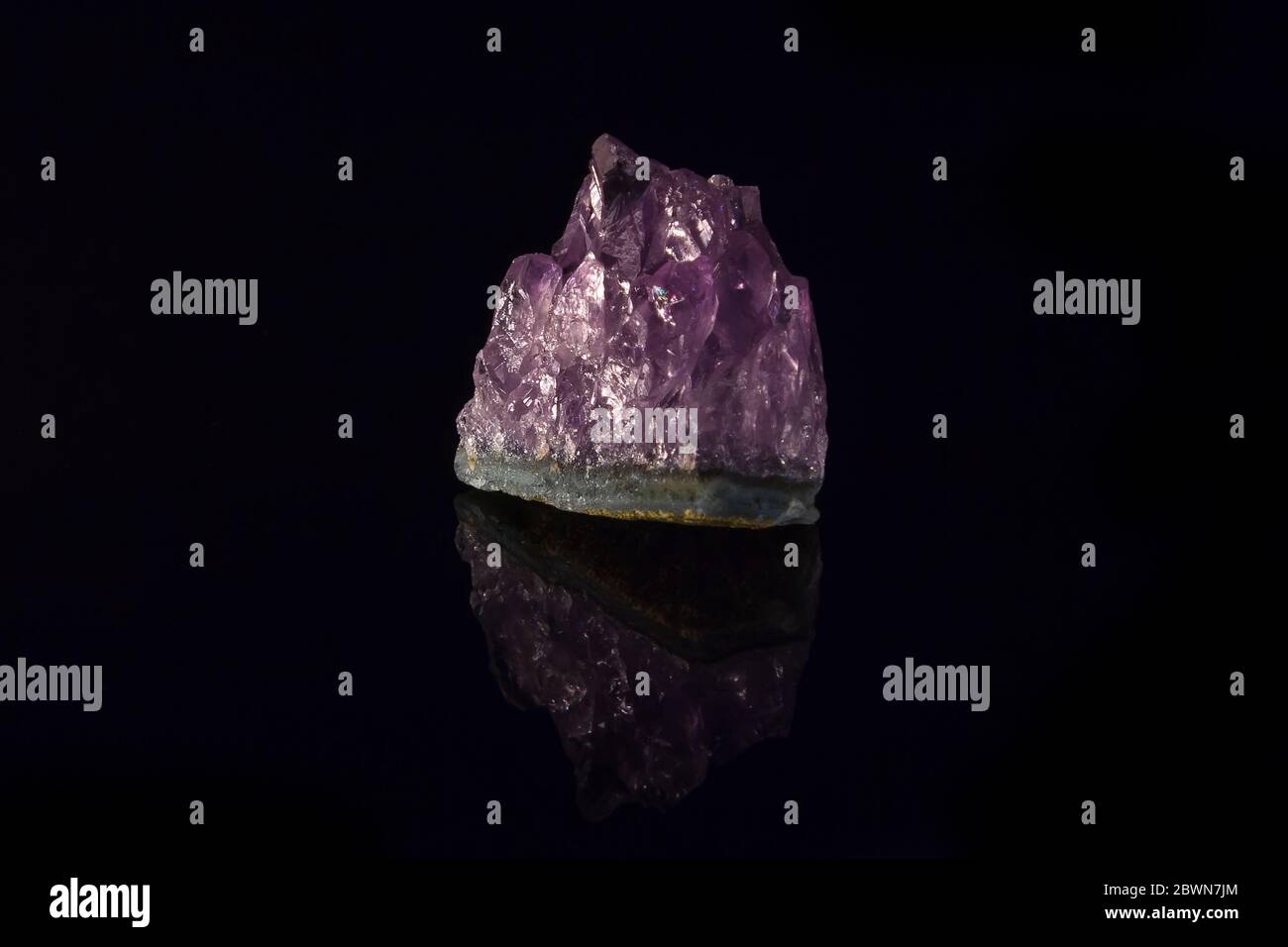 Purple amethyst semiprecious stone, isolated on black background, with reflection Stock Photo