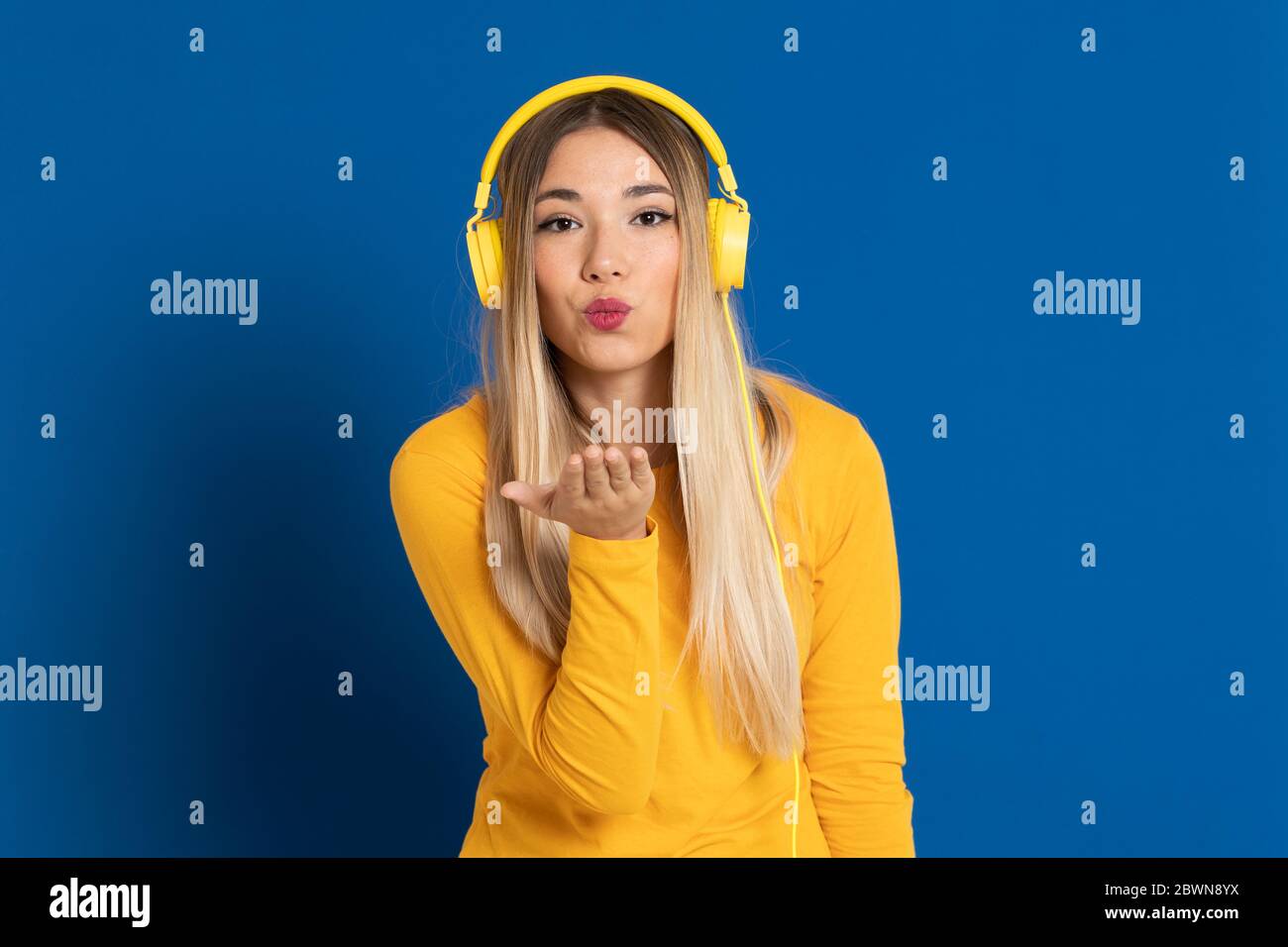 Blonde girl yellow headphones on a blue background Stock Photo Alamy