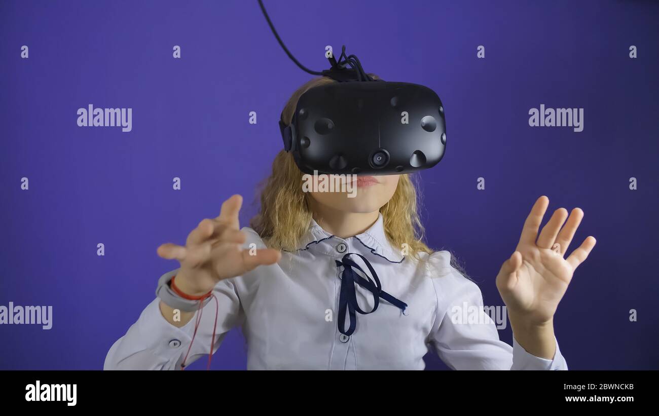 A teenage girl plays a virtual game in black virtual reality glasses. Stock Photo