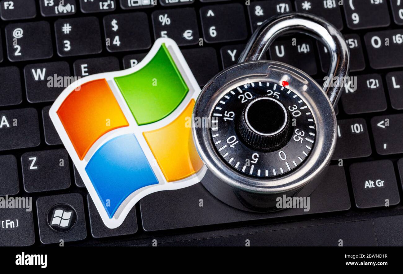 Microsoft Windows logo and a coded padlock, code lock symbol laying on a laptop keyboard. System safety and data security, hacking, exploits abstract Stock Photo