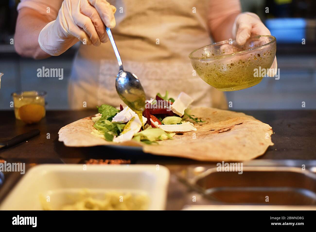 woman fills and rolls a vegetable wrap Stock Photo