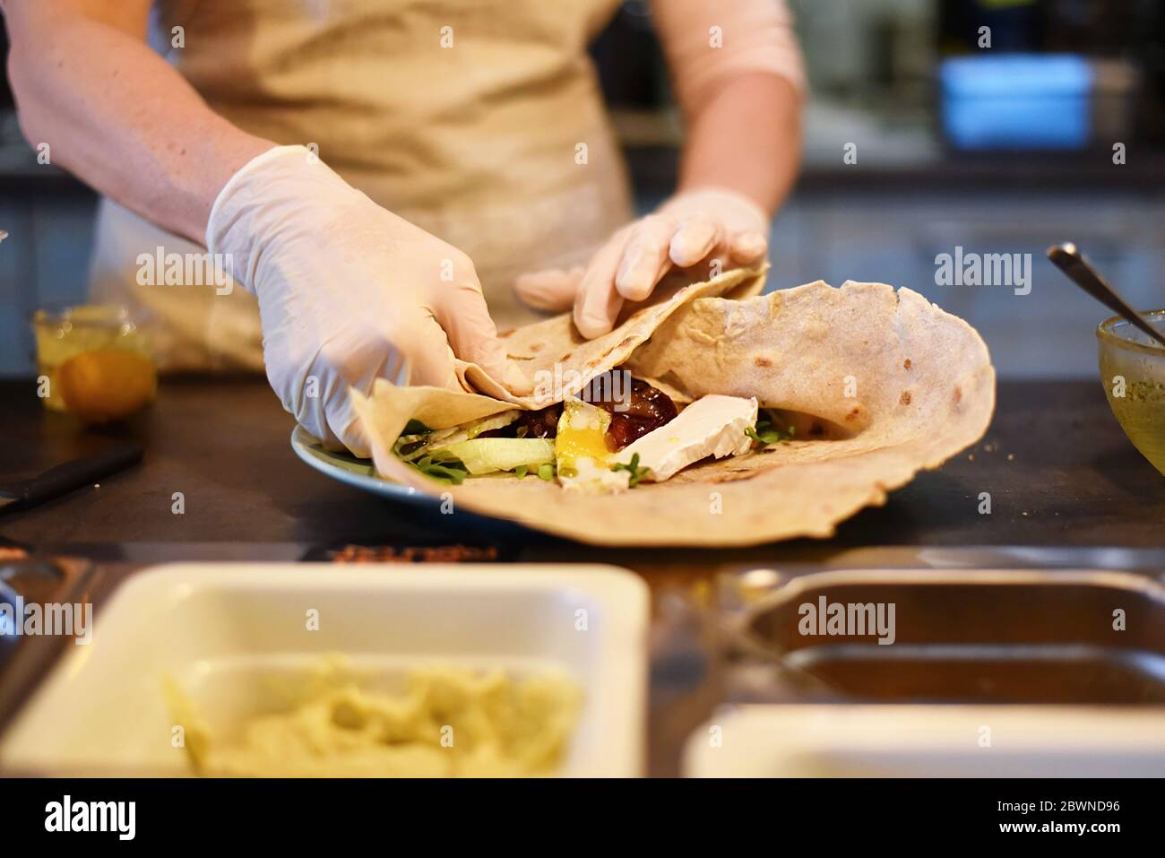 woman fills and rolls a vegetable wrap Stock Photo
