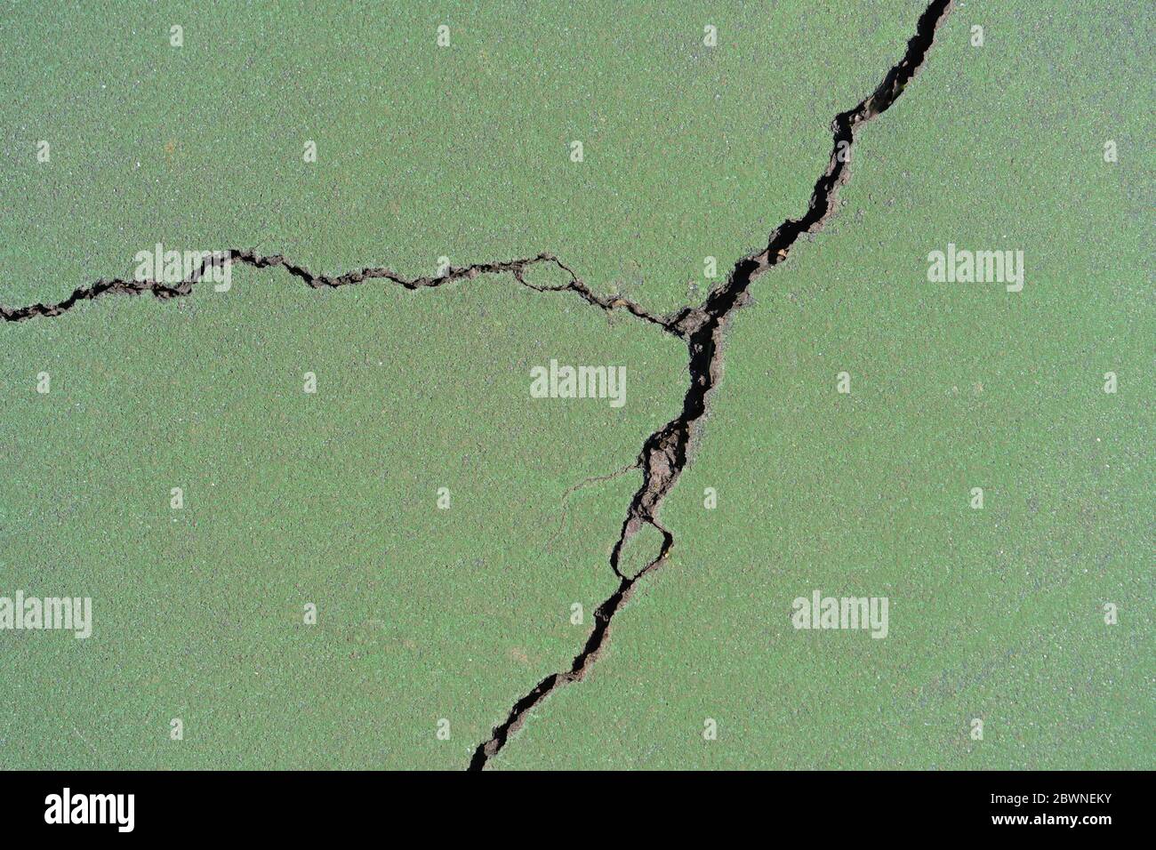 background of a crack in green painted blacktop of a tennis court Stock Photo