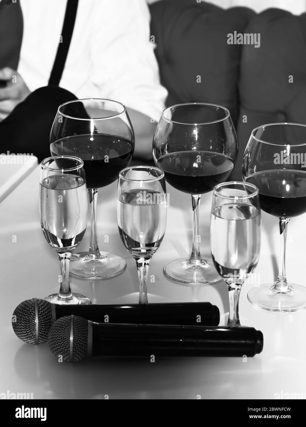 White and red wine, alcoholic drink, beverage, served in different glasses and two wireless microphones on white table Stock Photo