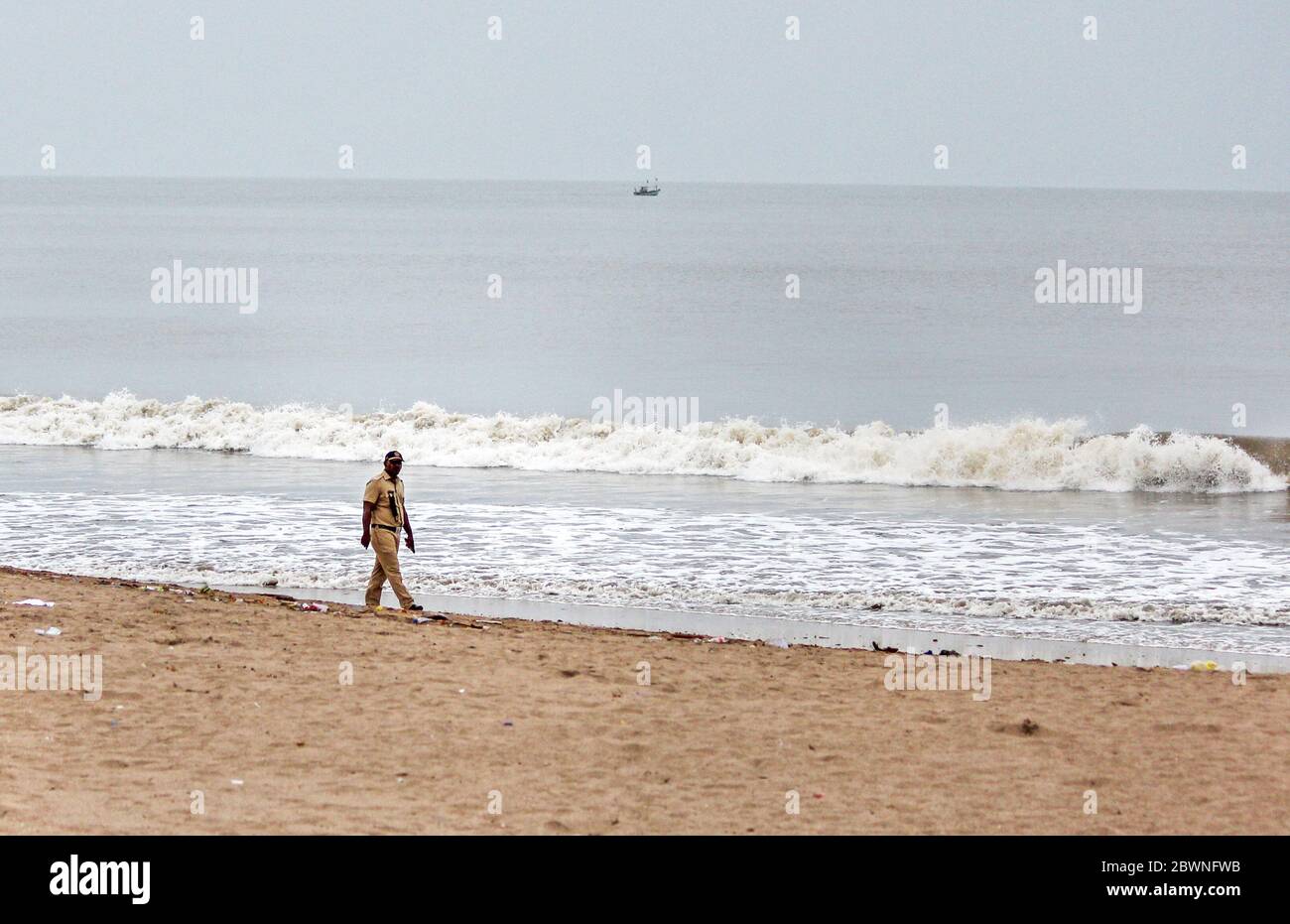 A policeman patrols the beach in preparation for the cyclone.India Meteorological Department (IMD) says that tropical cyclone ‘Nisarga’ has headed for the Maharashtra coast. People have been advised to stay indoors, be prepared to face possible power cuts as strong winds hit the city. National Disaster Response Force (NDRF) has positioned nine teams in vulnerable districts. Stock Photo
