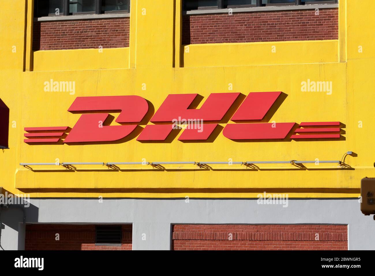 A DHL shipping logo against a yellow wall on one of their warehouses Stock Photo
