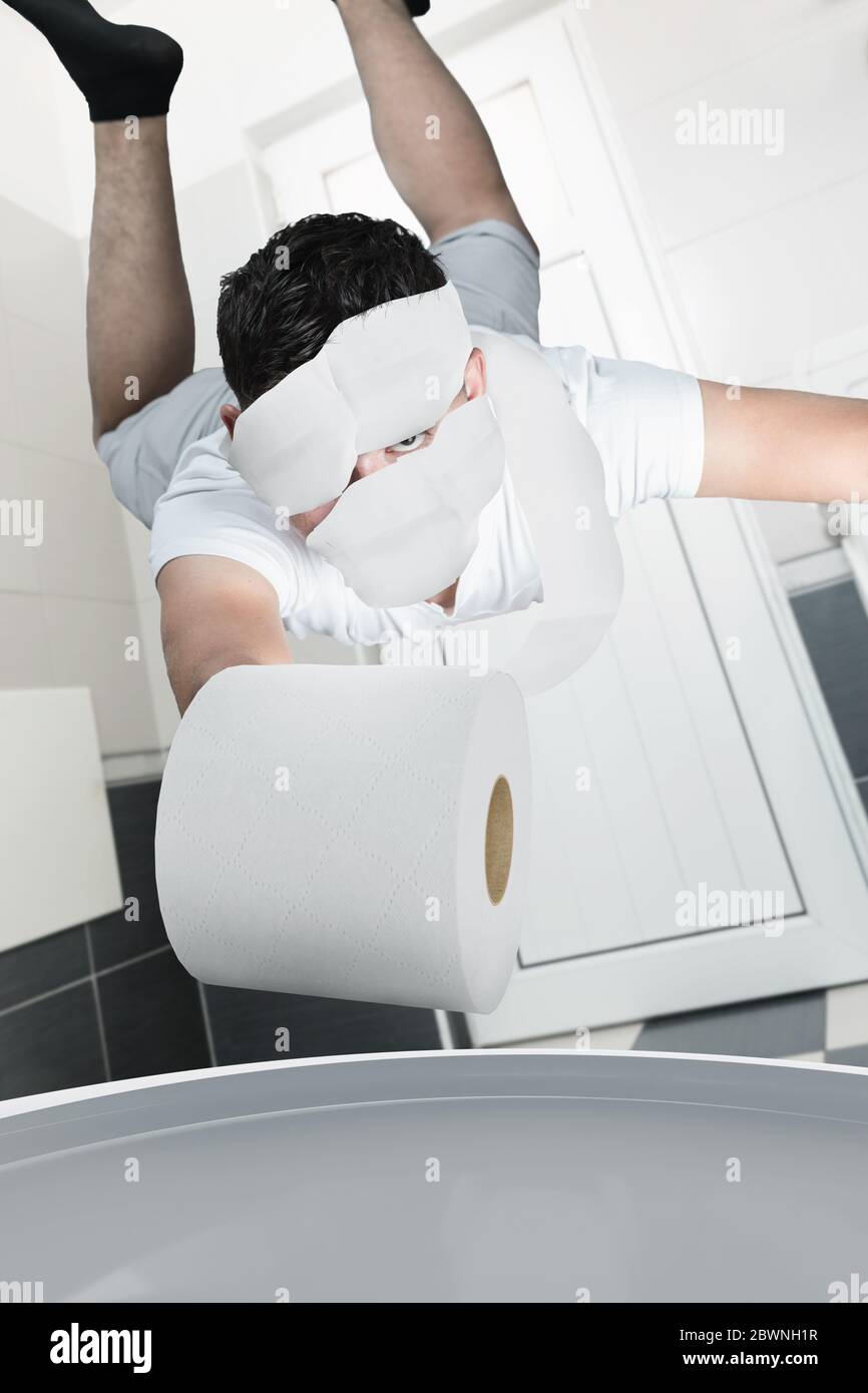 young man covered with toilet paper flying after toilet roll which falling into toilet water Stock Photo