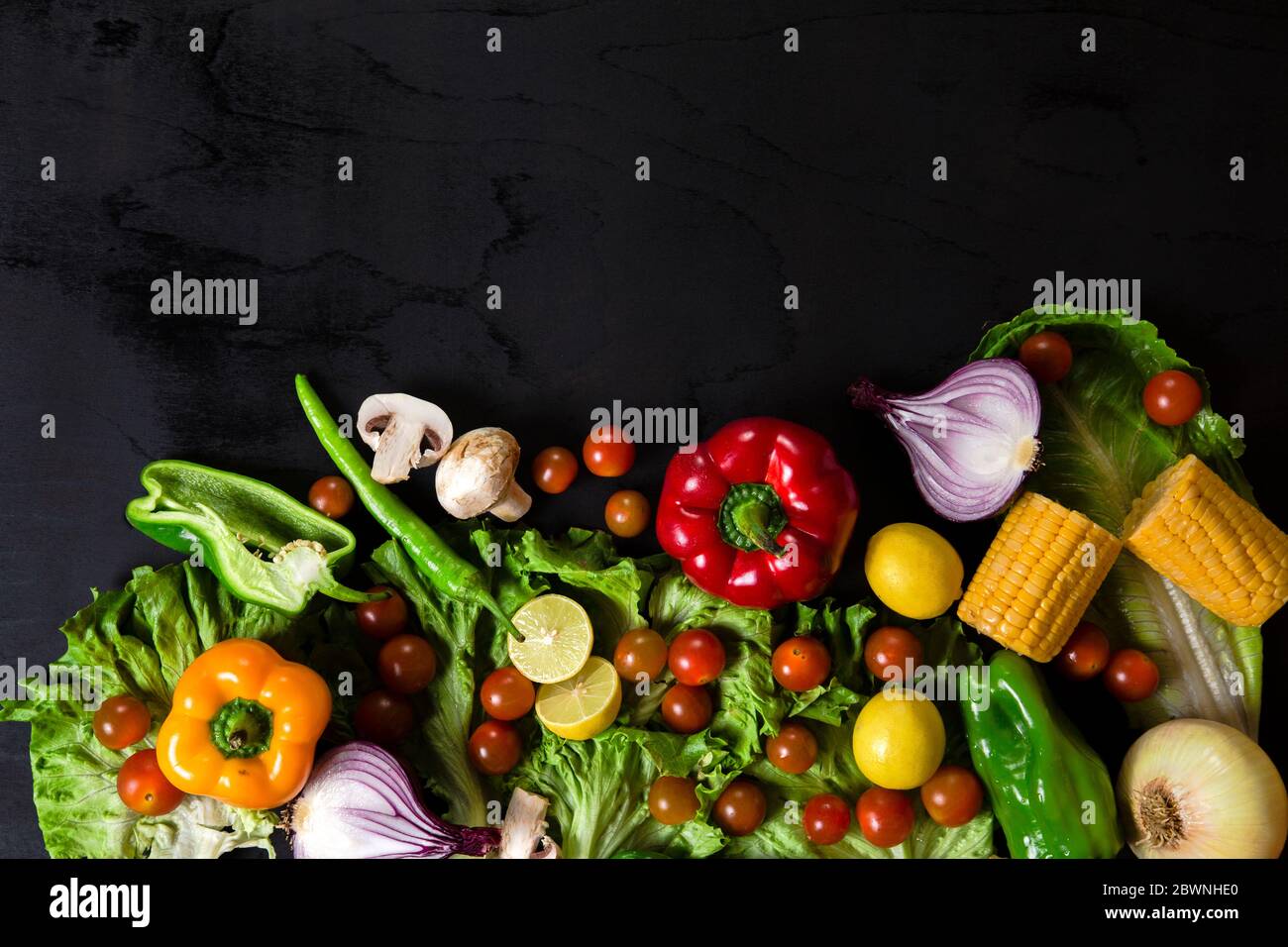 Various fresh vegetables arranged on black surface Stock Photo