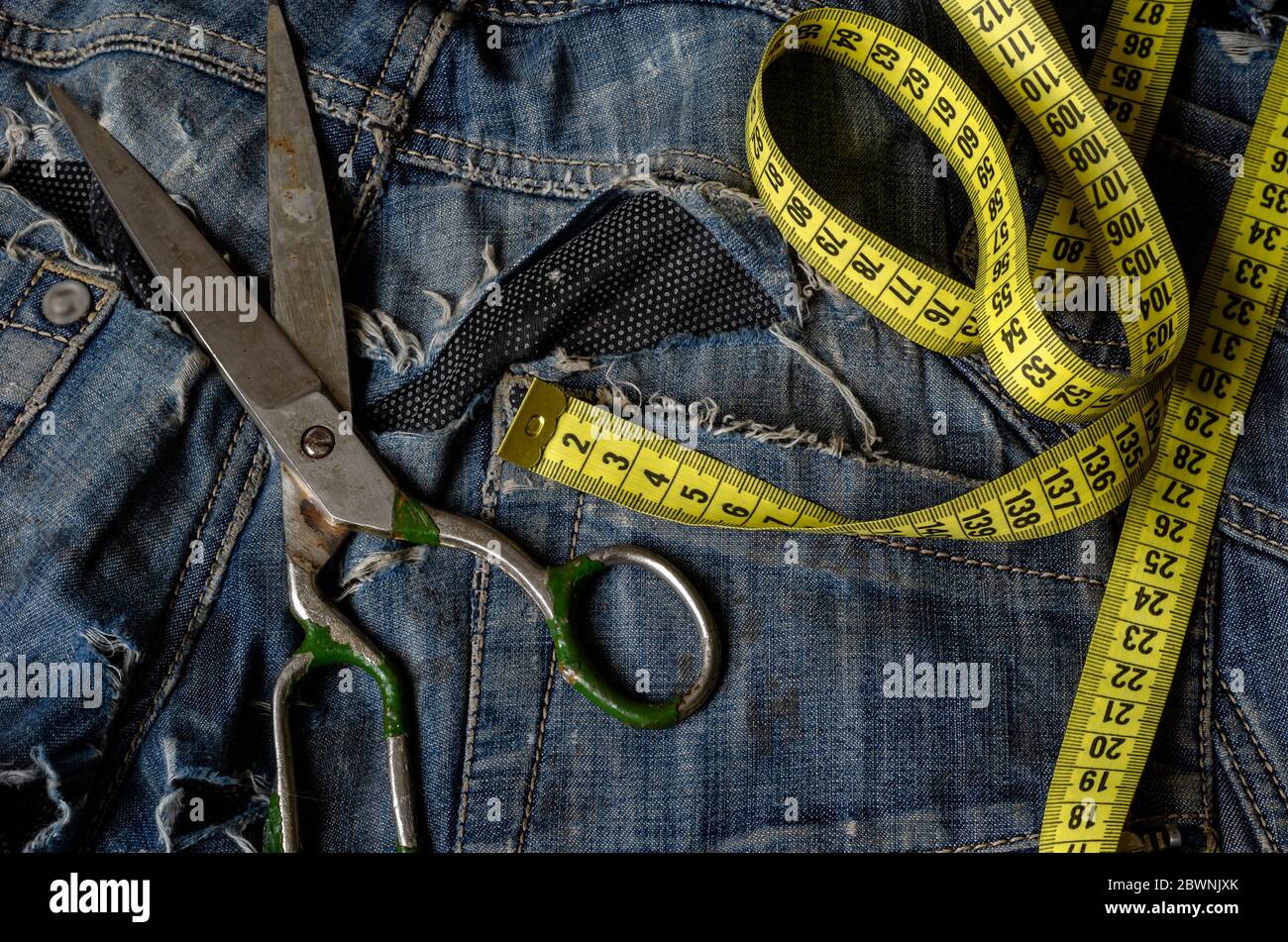 https://c8.alamy.com/comp/2BWNJXK/tailoring-and-design-concept-metal-scissors-ruler-and-yellow-measure-tape-in-denim-pants-pockets-small-business-clothing-repair-services-2BWNJXK.jpg