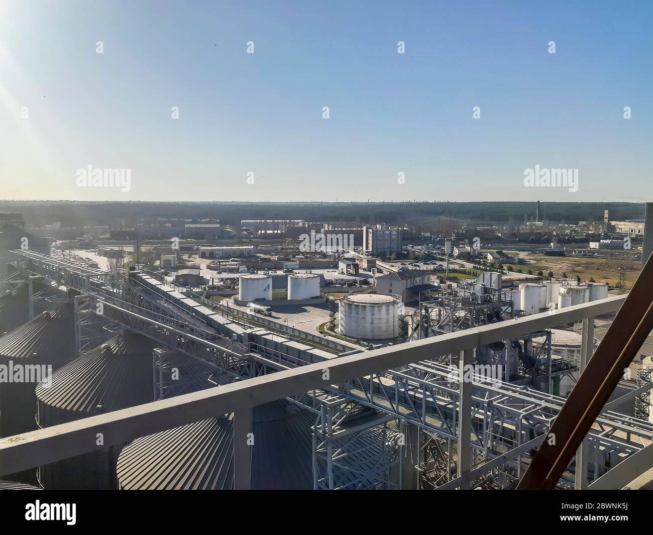 Grain and oil terminals of a modern sea commercial port top view. In the foreground is a silo for storing grain. Tanks for oil and fuel in the backgro Stock Photo