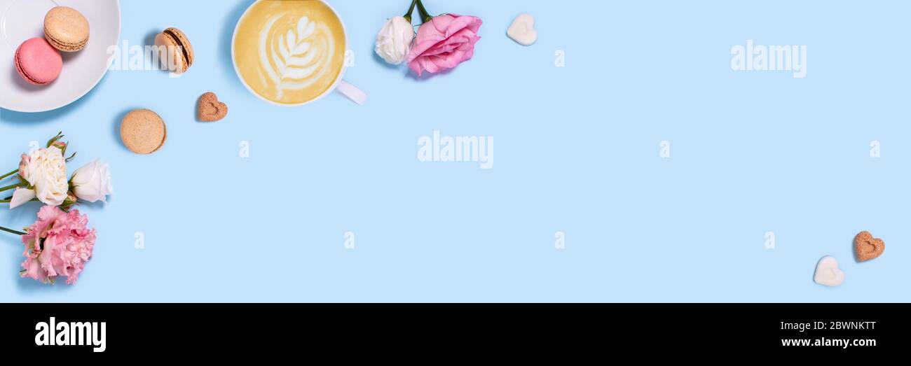 Blue background with macaroons and a Cup of coffee surrounded by peonies and roses. Top view with space for your text. Stock Photo